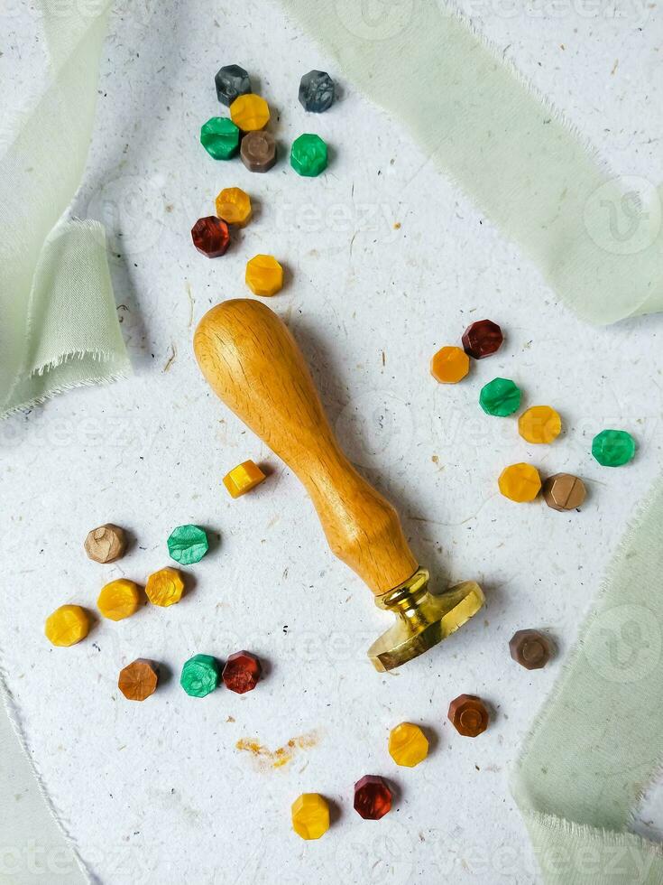 a top view of colorful wax bead and sealing wax with green silk ribbon on an old grey surface photo