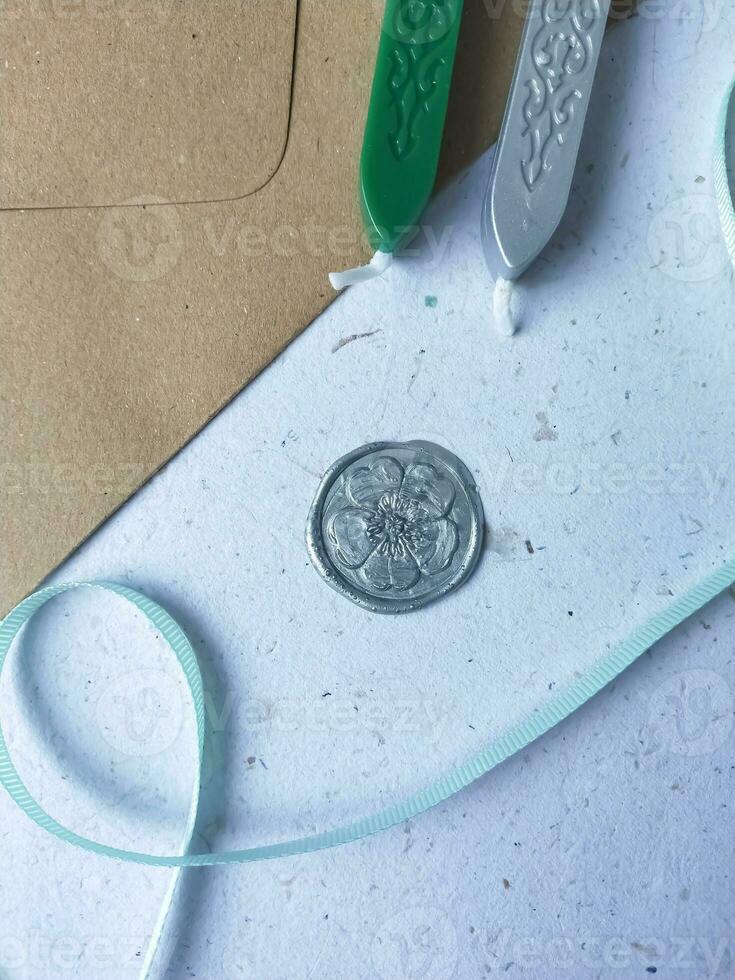 a vertical shot of wax coin with ribbon, wax bead on grey surface photo