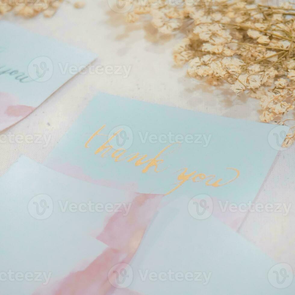 Card with text thank you and dry flowers on white wooden background photo