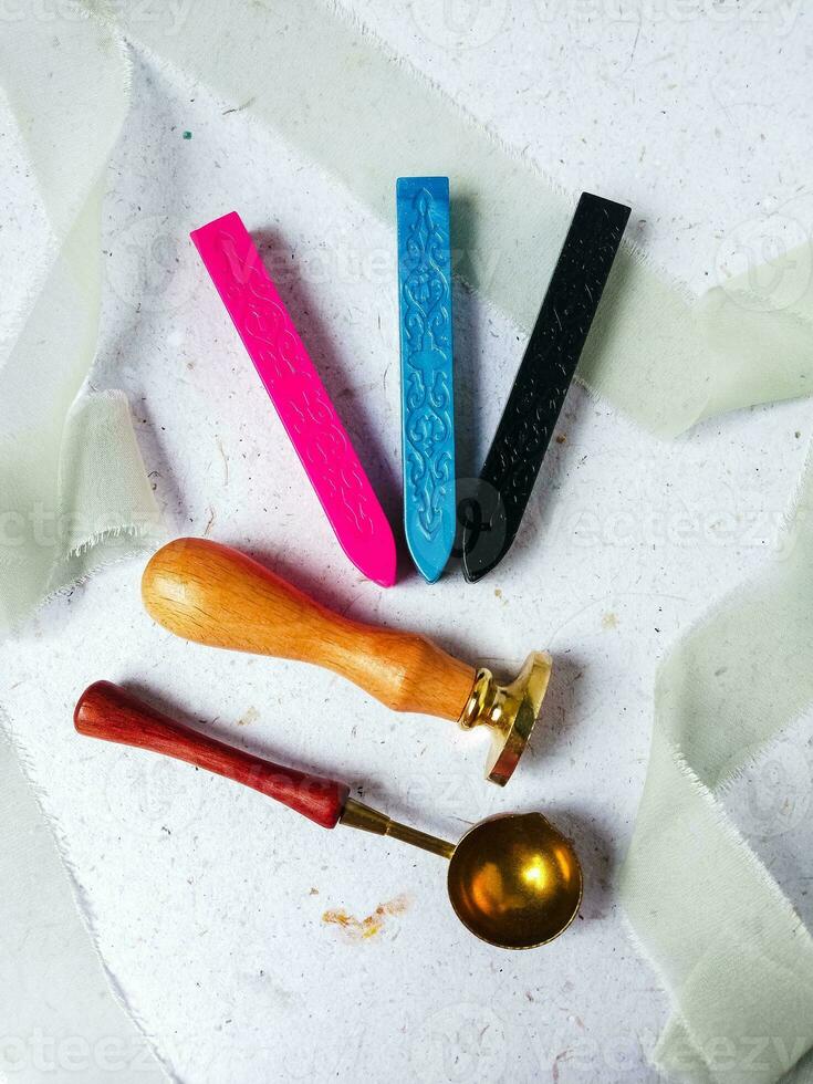 a top view of colorful wax bead and sealing wax with green silk ribbon on an old grey surface photo