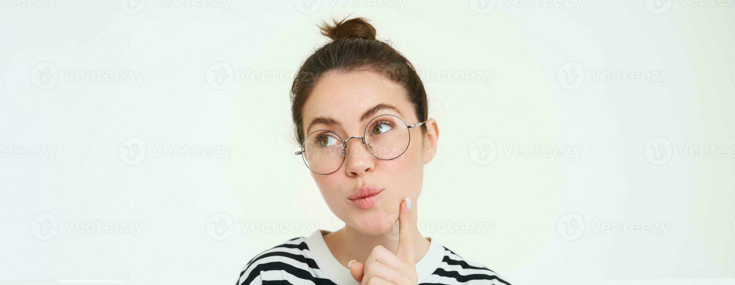 Image of woman in glasses, thinking, pondering smth, looking away with thoughtful face, analizing, standing over white background photo