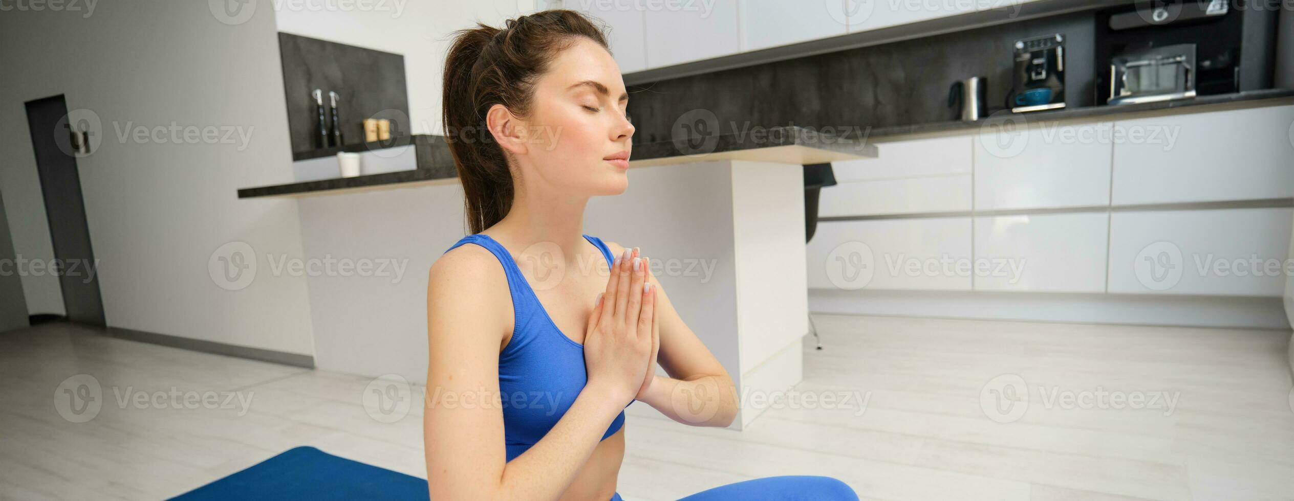 Sport and fitness. Close up portrait of cute girl doing yoga, clasps her hands together and does deep breathing training, workout at home photo