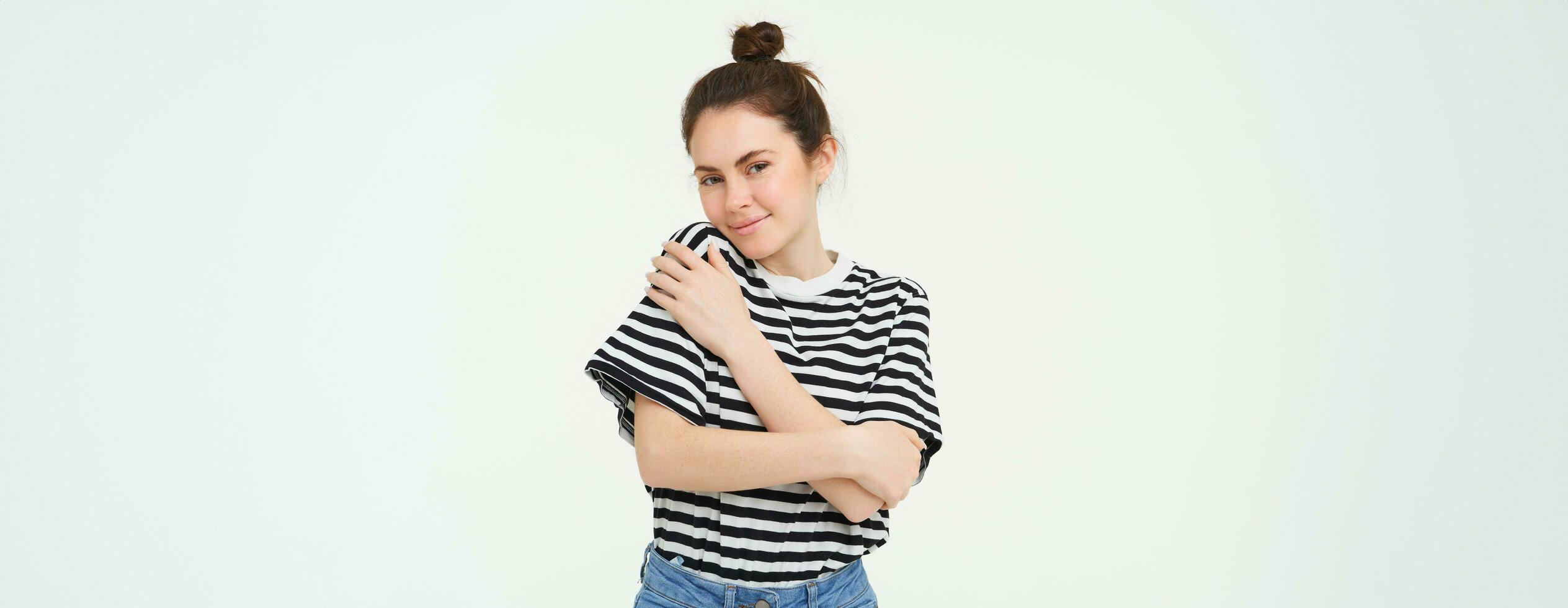 Image of tender, beautiful brunette girl, hugging herself, concept of selfcare and love, standing over white background photo