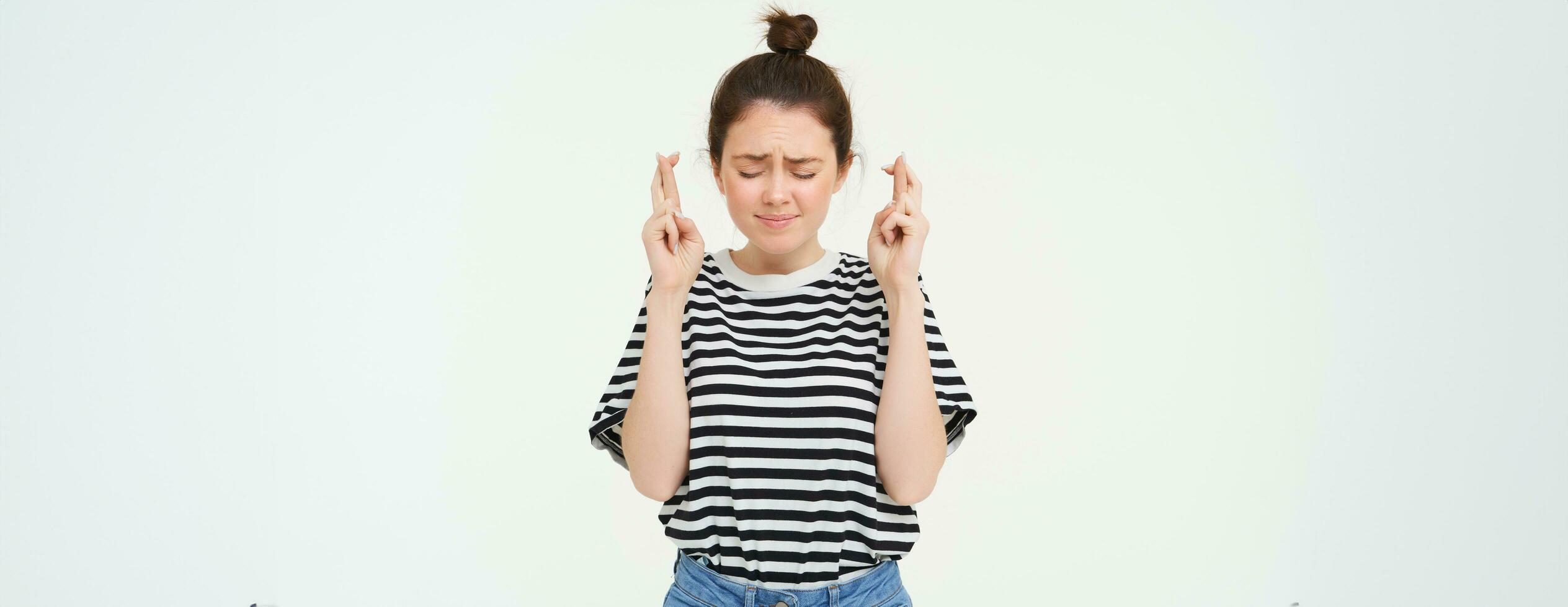 retrato de esperanzado joven mujer, hace desear, cruzar dedos para bueno suerte, deseando, anticipando, en pie terminado blanco antecedentes foto