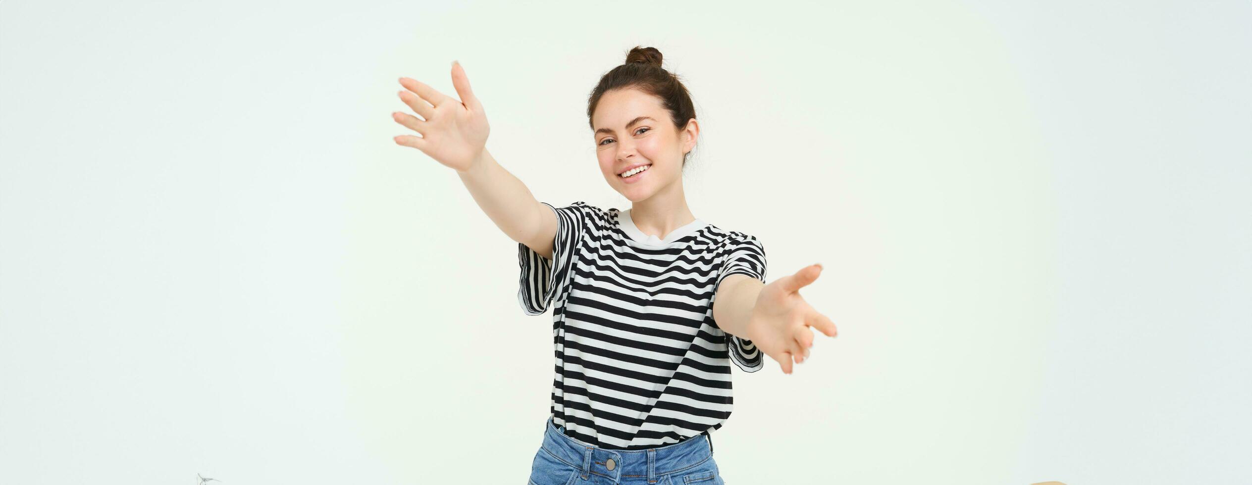 Portrait of cute smiling woman stretches her hands, reaches to hold something, wants to hug you, standing over white background photo