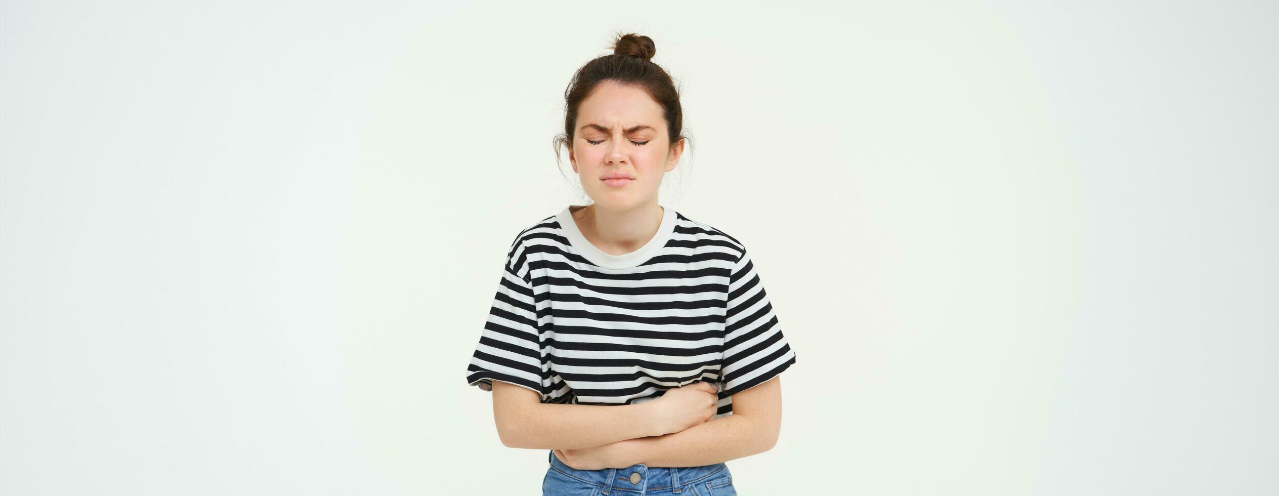 retrato de mujer haciendo muecas desde doloroso menstrual calambre, toques su barriga, incomodidad o estómago dolor, soportes terminado blanco antecedentes foto