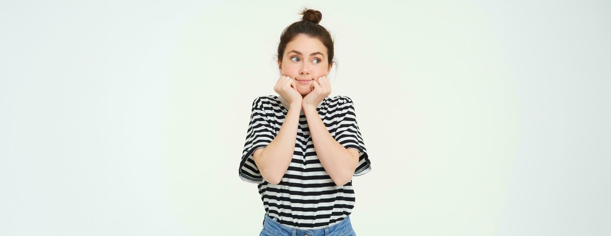 Wellbeing and women concept. Portrait of young woman with cute face, holds hands near head and smiles, isolated against white background photo