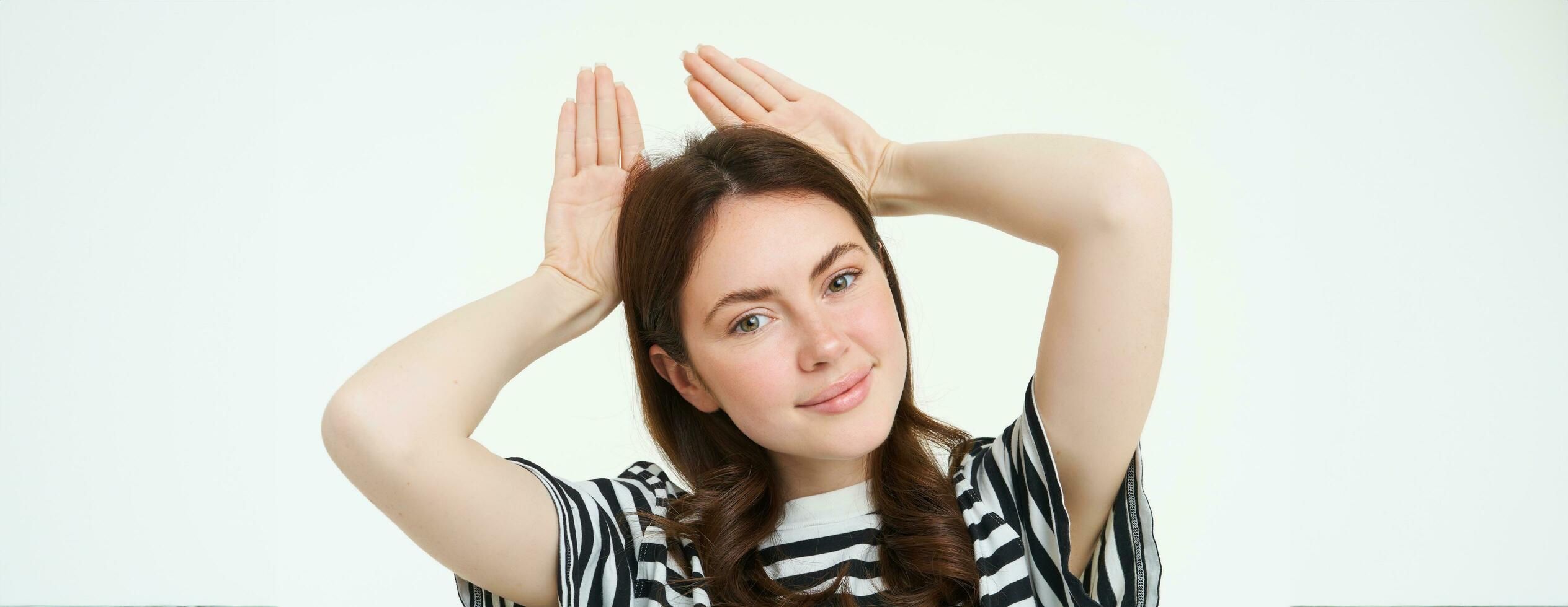 Image of beautiful young woman, posing with animal ears on head and smiling, making cute face, white background photo