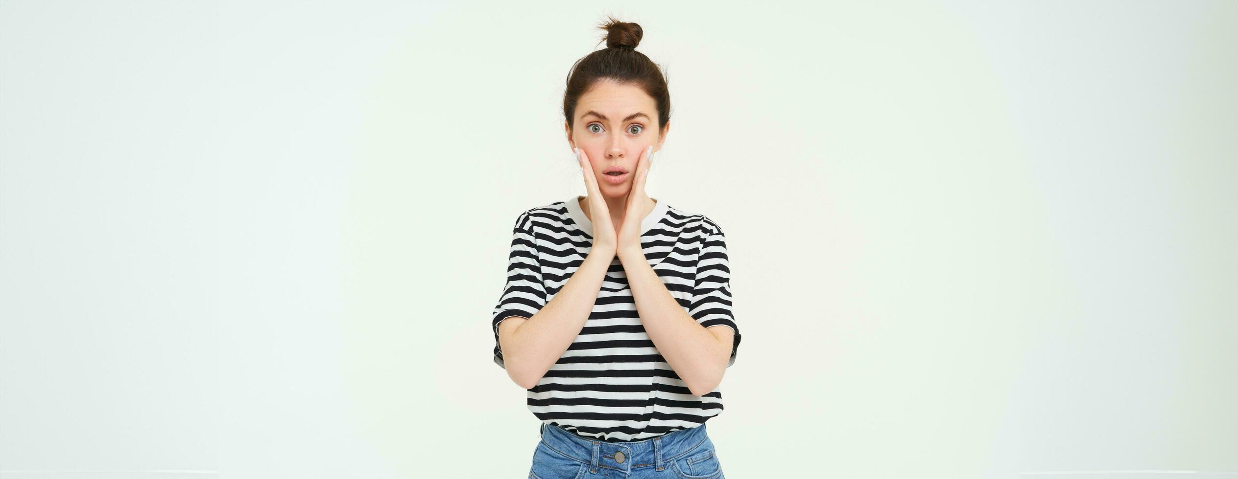 Lifestyle and emotions concept. Portrait of girl with surprised face expression, saying wow, looks impressed at camera, stands over white background photo