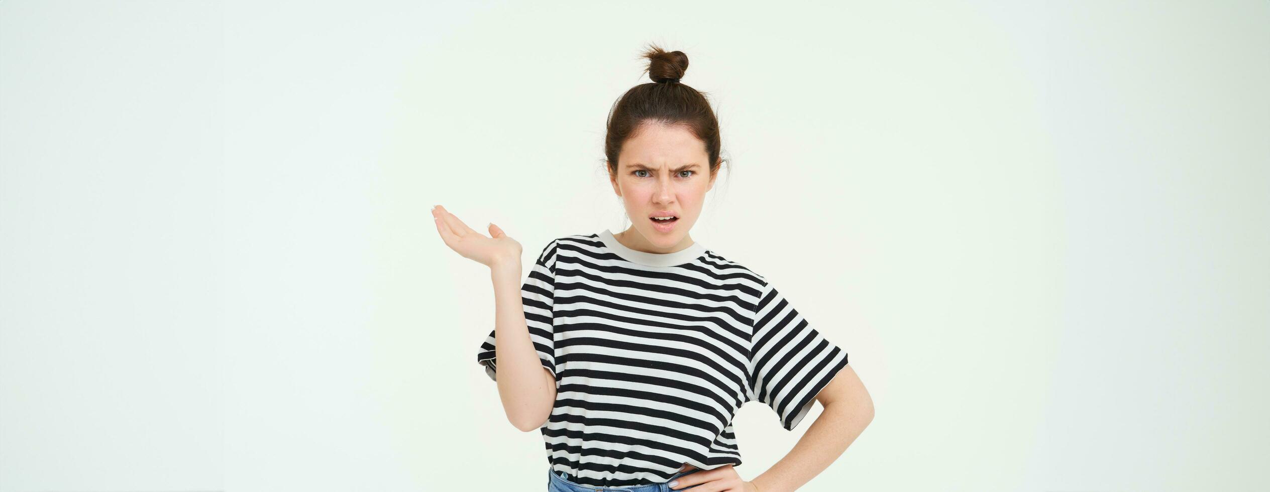 Portrait of angry woman complaining, raising one hand and shrugging looking frustrated, waiting for explanation, doesnt udnerstand smth, standing over white background photo