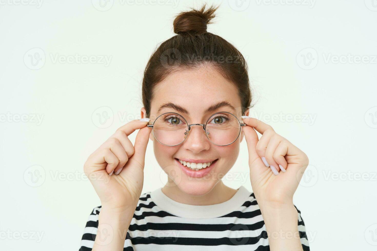 Close up portrait of beautiful woman, trying on new glasses, buying eyewear, smiling and looking happy, standing over white background photo