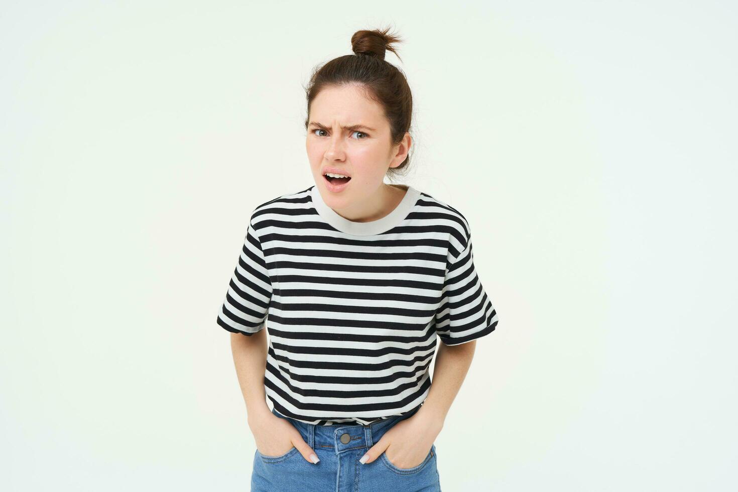 Portrait of young woman with shocked, angry face expression, hear something disappointing, shows negative, frustrated reaction, standing over white background photo