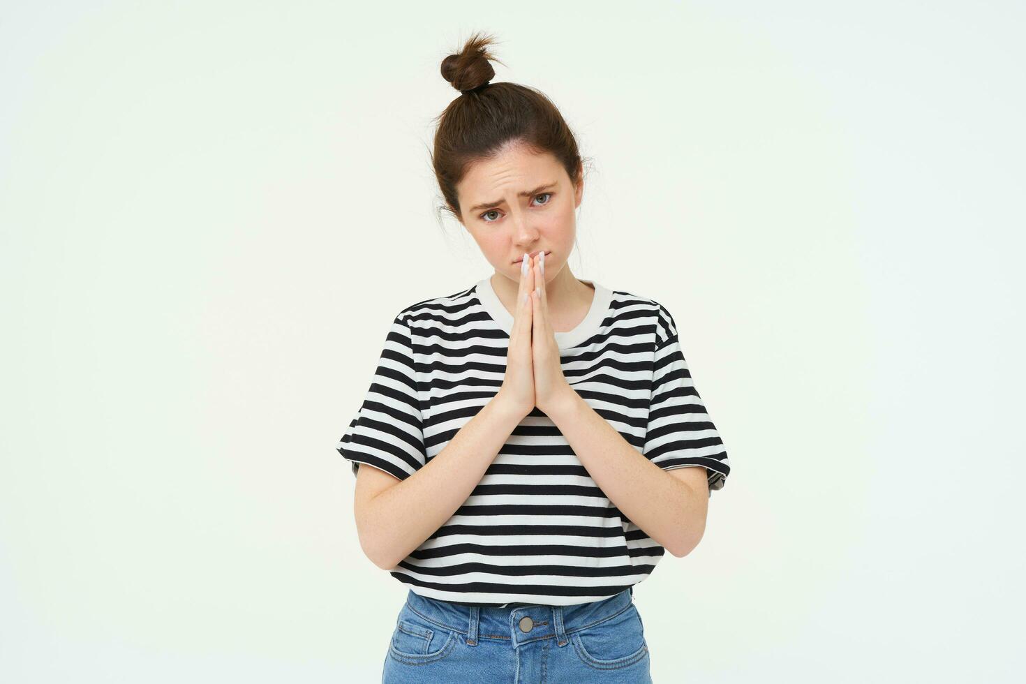 Please. Young woman asks for help, begs you, holds hands in pray, pleading, isolated against white background photo