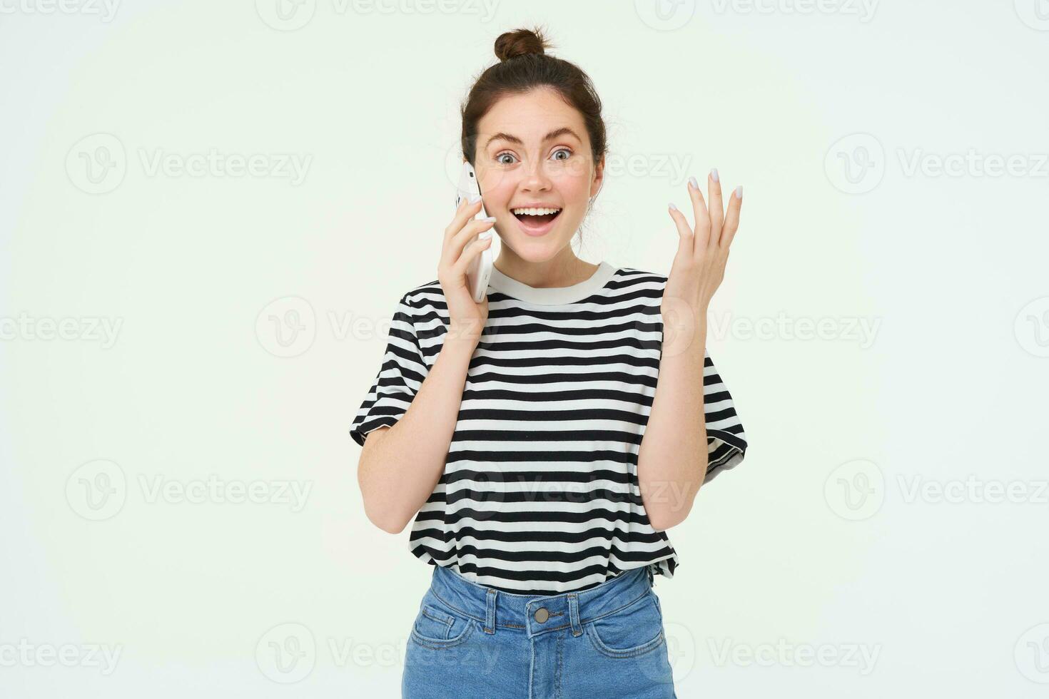 retrato de emocionado mujer respuestas teléfono llamar, reacciona asombrado a maravilloso Noticias recibido terminado el teléfono, en pie terminado blanco antecedentes foto