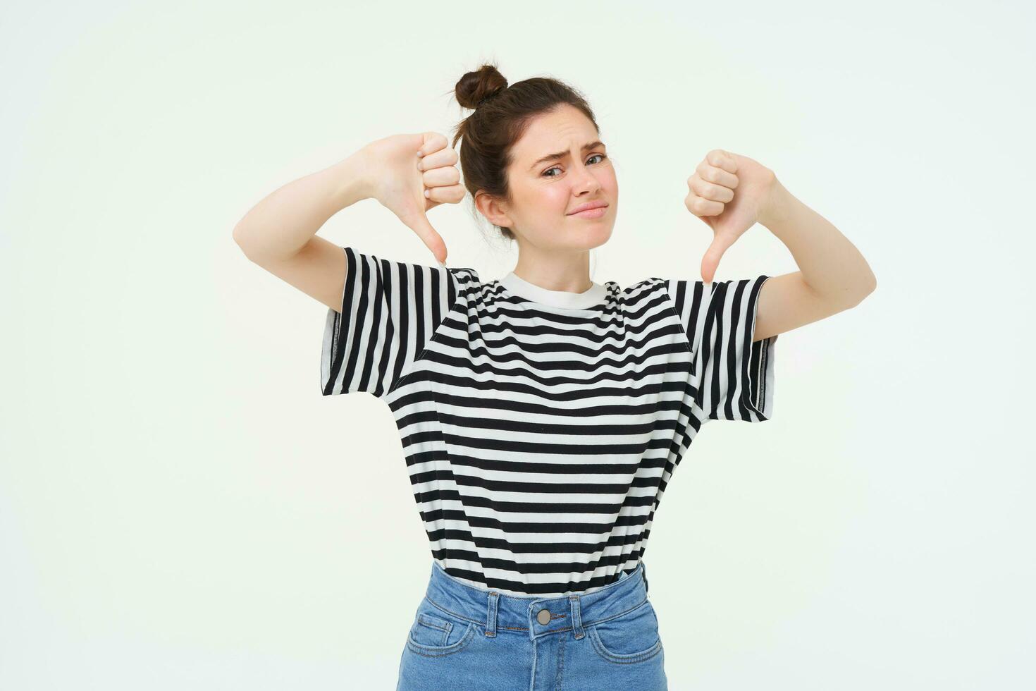 joven mujer da negativo comentario, muestra pulgares abajo, desaprueba producto, no le gusta algo malo, soportes terminado blanco antecedentes foto