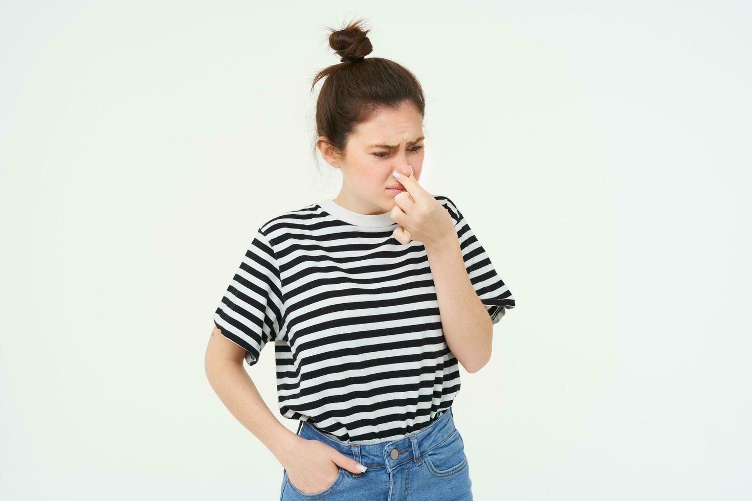 Image of woman digusted by smell, shuts her nose and grimaces, isolated over white background photo