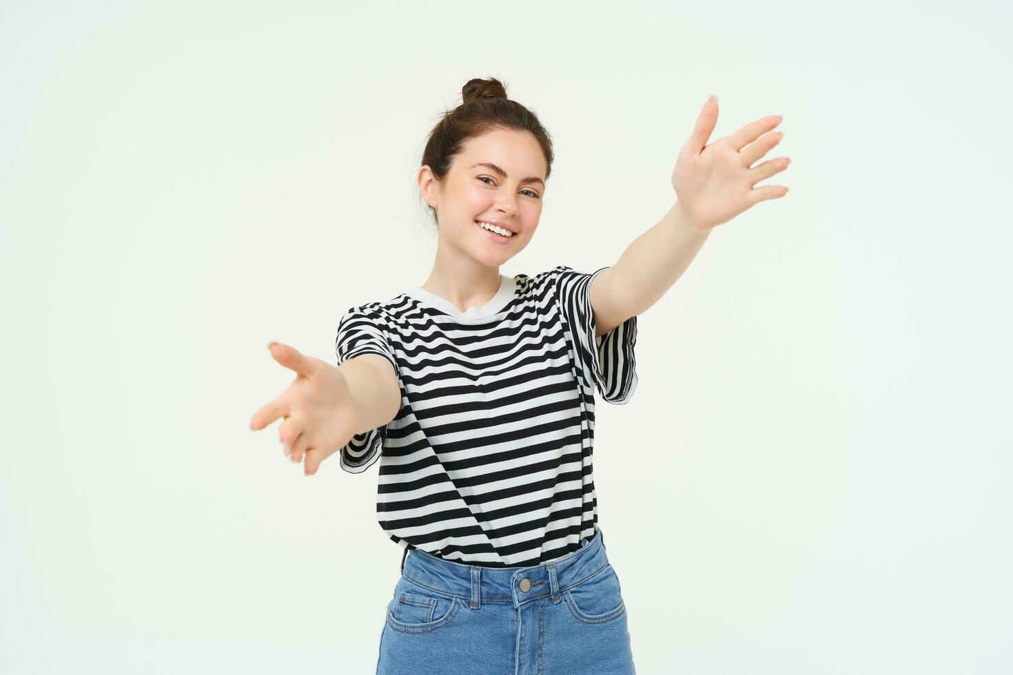 Portrait of cute smiling woman stretches her hands, reaches to hold something, wants to hug you, standing over white background photo