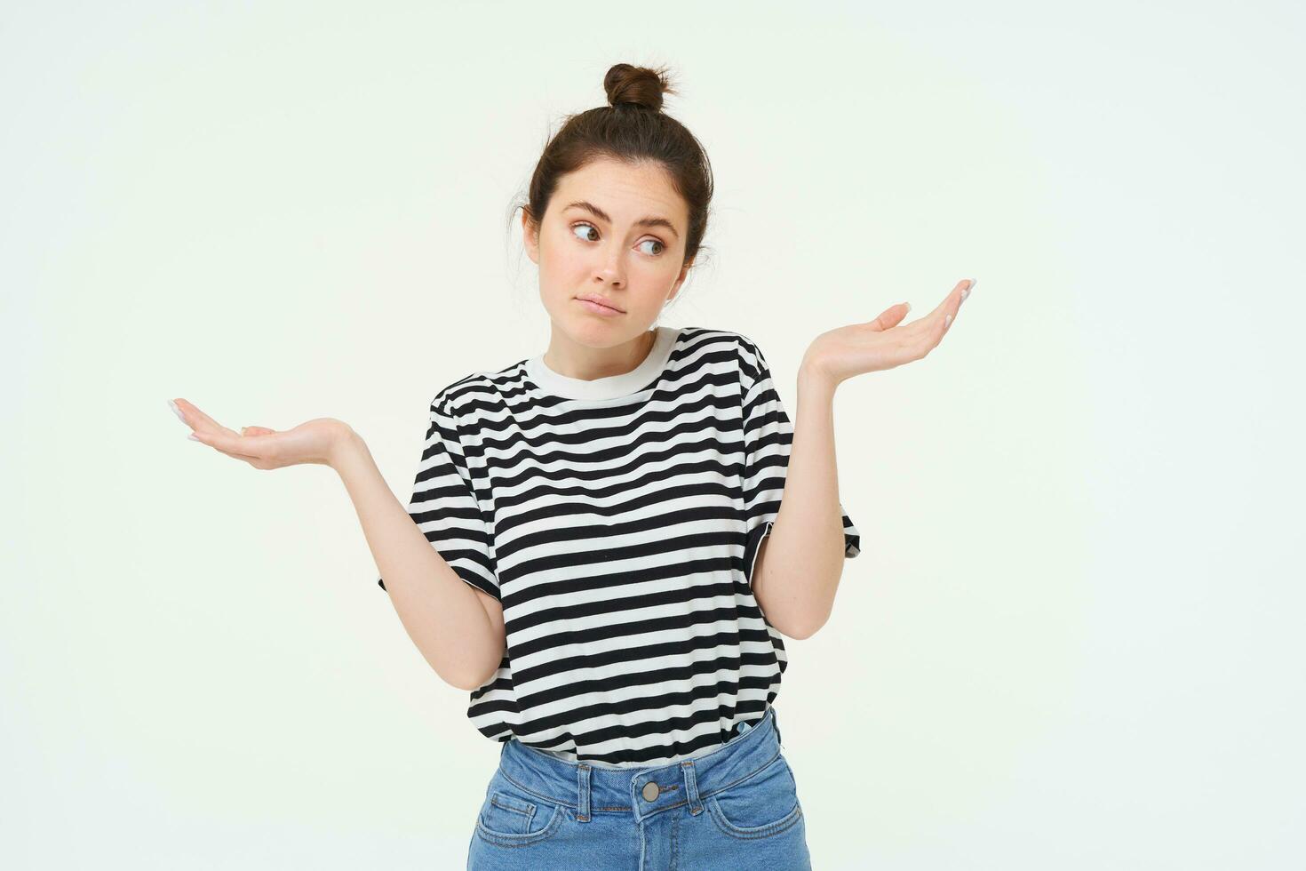 I dont know. Clueless young woman shrugging shoulders, looks confused, stands against white studio background photo