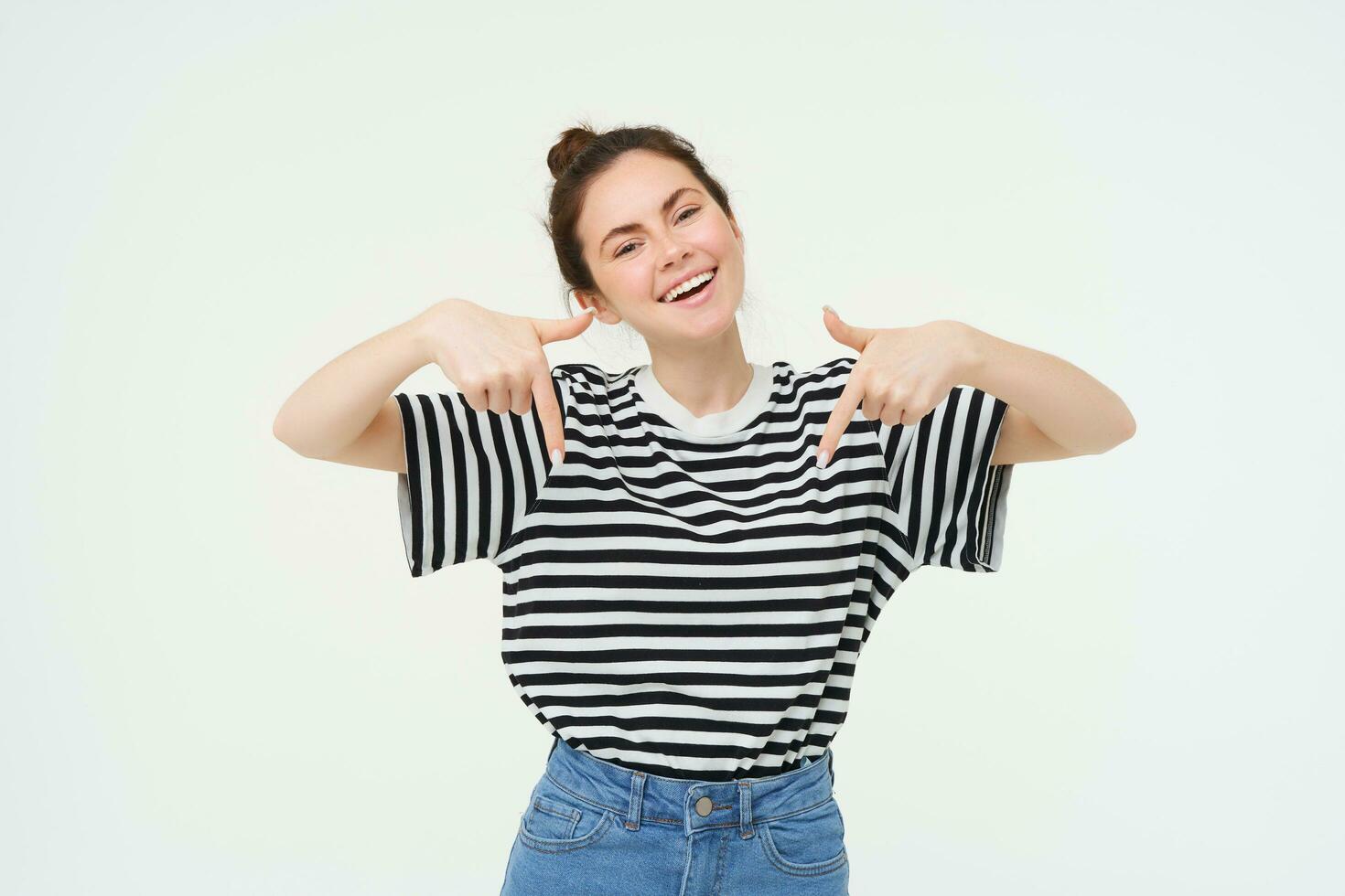 Enthusiastic girl points fingers down, shows advertisement, promo banner below, stands over white background photo