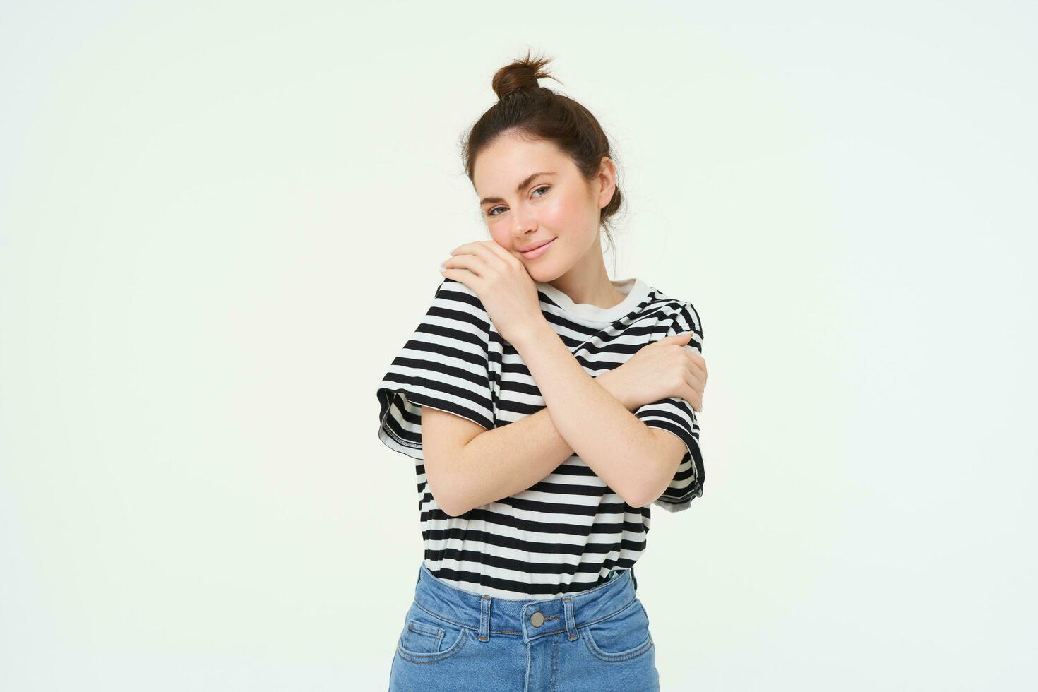 Image of tender, beautiful brunette girl, hugging herself, concept of selfcare and love, standing over white background photo