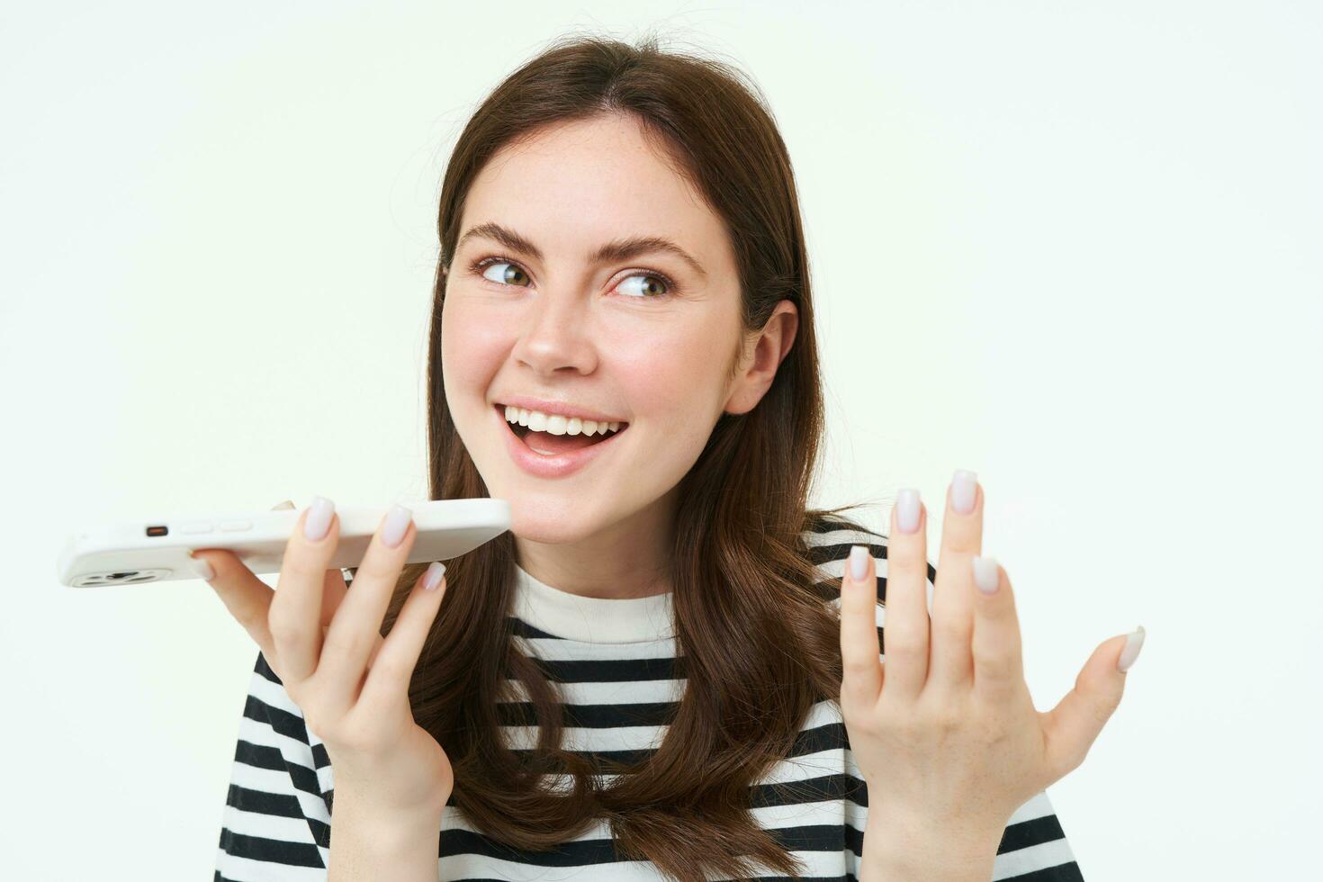 Portrait of happy young woman, student recording voice message, holding smartphone near lips, talking into mobile phone speakerphone, explaining something, singing, translating her words photo
