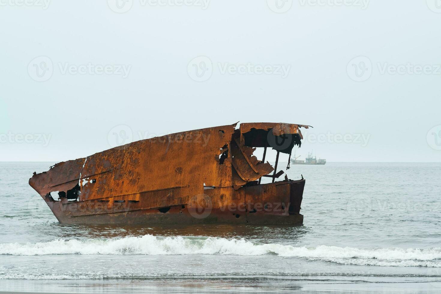 oxidado naufragio en contra un brumoso marina con un Embarcacion en el distancia foto