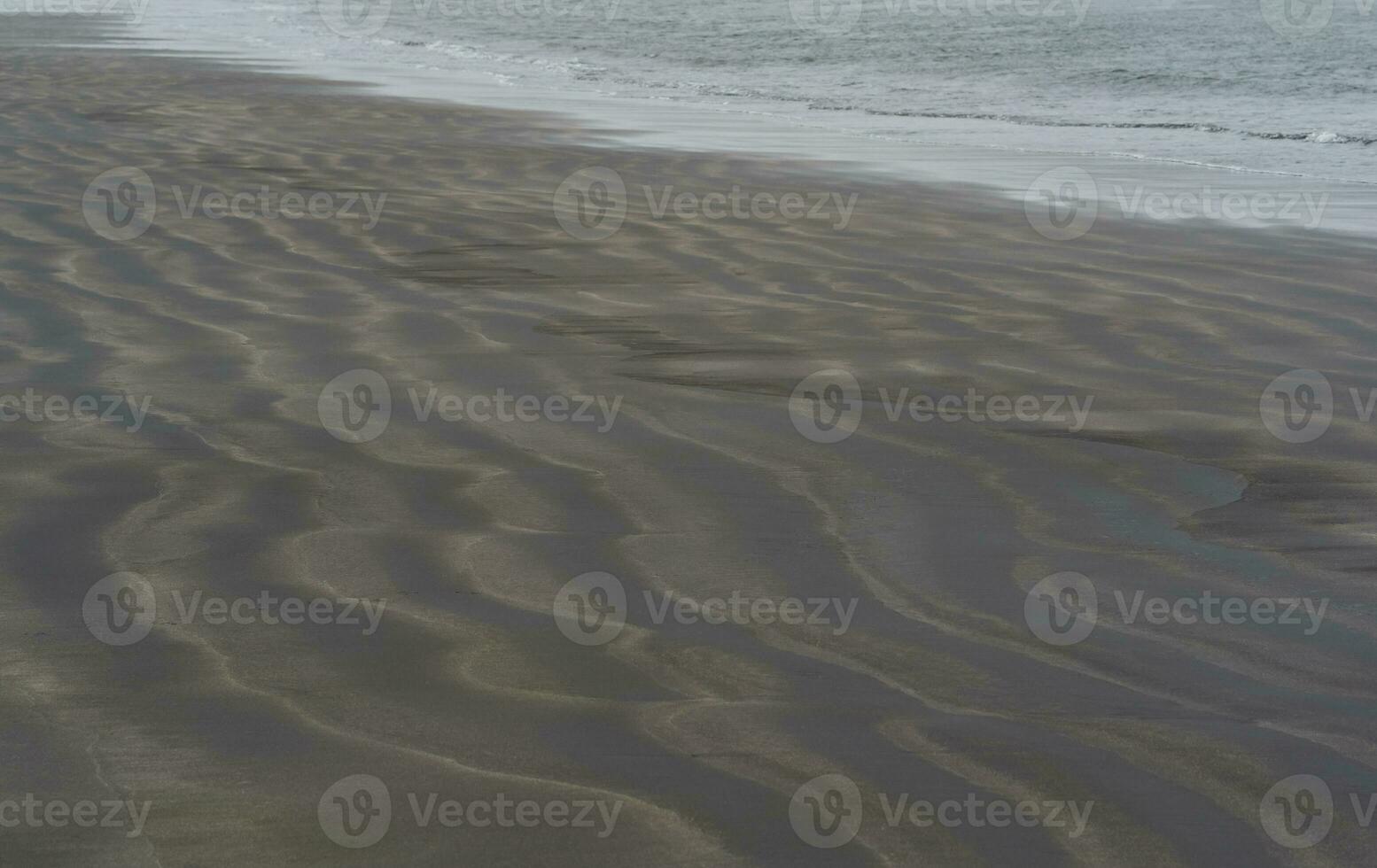 black volcanic sand beach with wave patterns photo