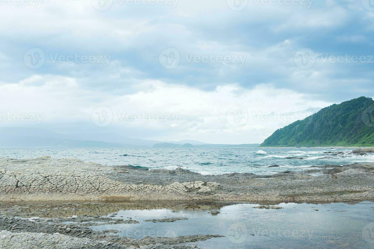 coastal landscape  with beautiful columnar basalt cliff on the wooded coast of Kunashir island photo