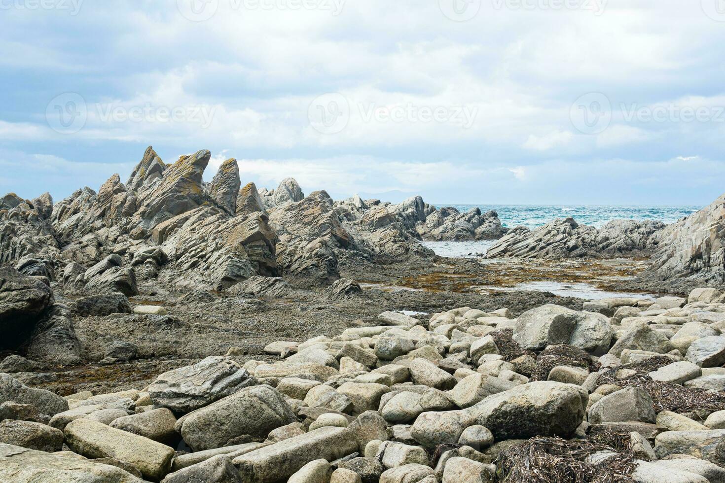sharp jagged basalt rocks on the sea coast, Cape Stolbchaty on Kunashir Island photo