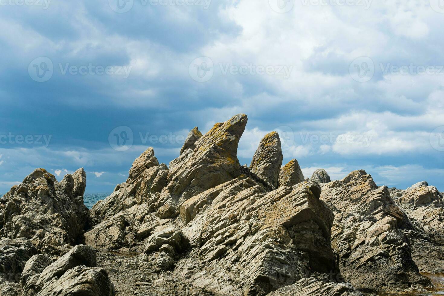 sharp jagged basalt rocks on the sea coast, Cape Stolbchaty on Kunashir Island photo