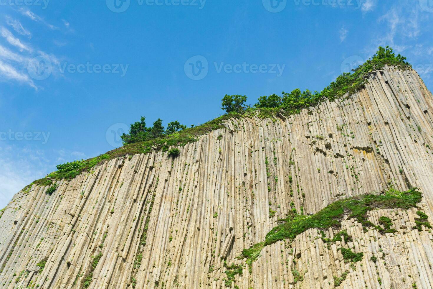 top of columnar volcanic basalt cliff against the background of the sky with clouds photo