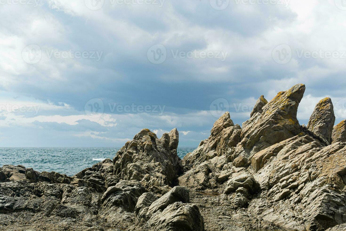 basalt rocks on the sea coast, Cape Stolbchaty on Kunashir Island photo