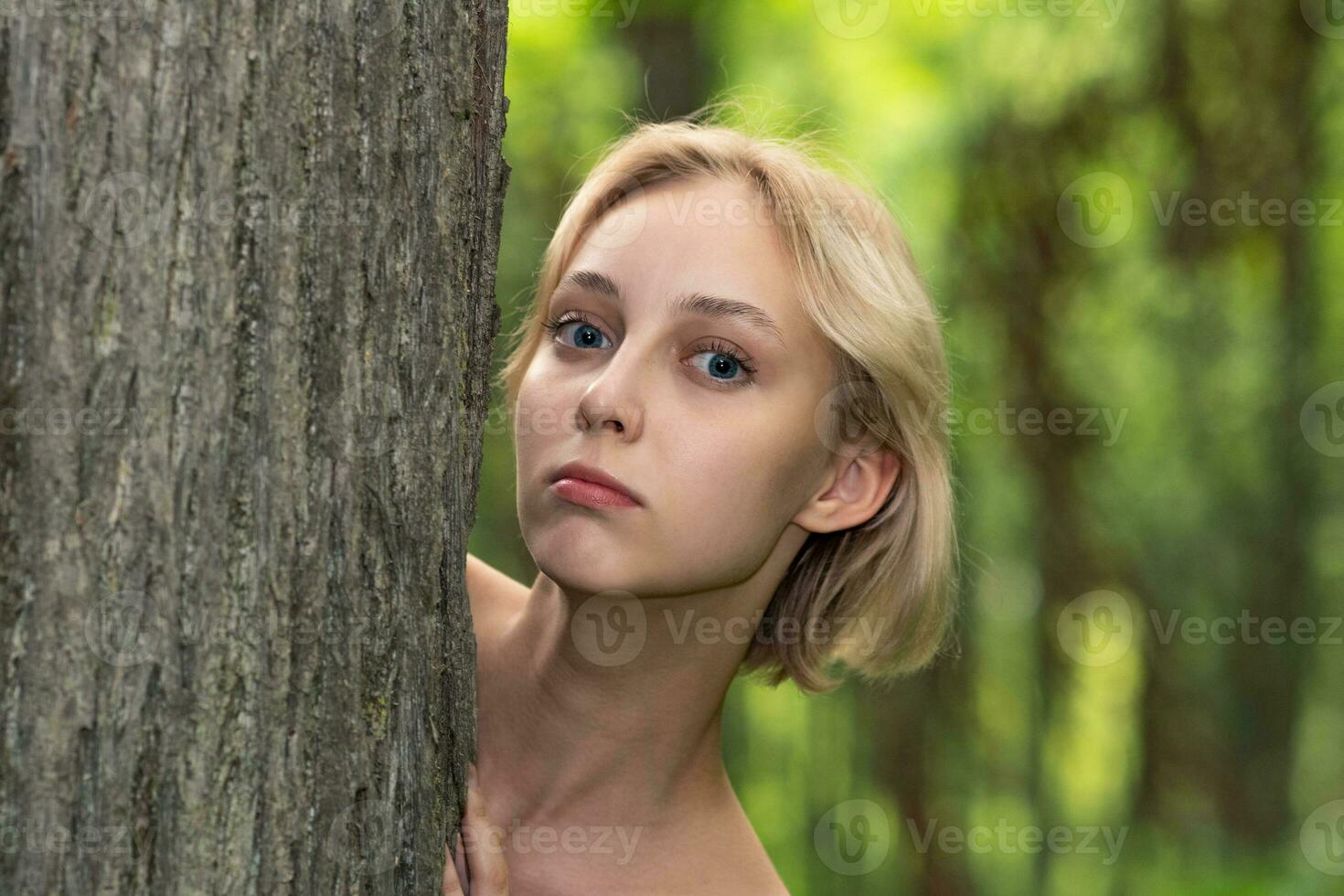 hermosa joven mujer siguiente a el árbol en el bosque foto