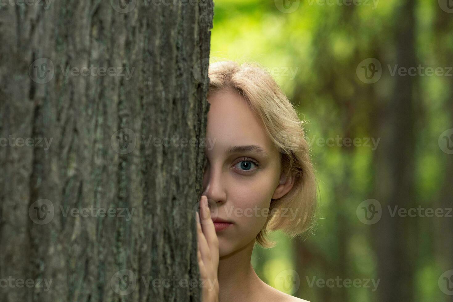 linda joven mujer siguiente a el árbol en el bosque foto