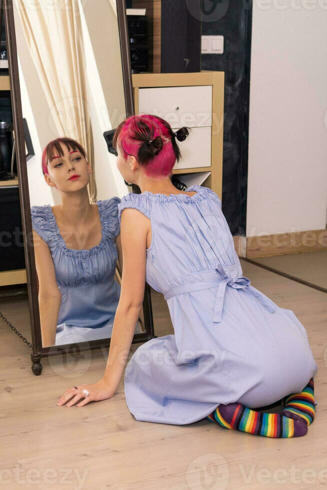 teenager girl looks in the mirror indoor, sitting on the floor photo