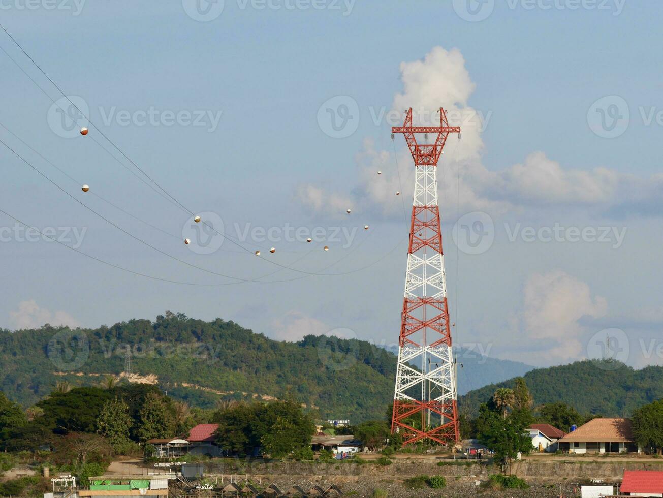 High voltage power lines tower on green mountain, Red high Pylon high-voltage power lines, high voltage electric transmission tower for producing electricity at high voltage electricity poles photo
