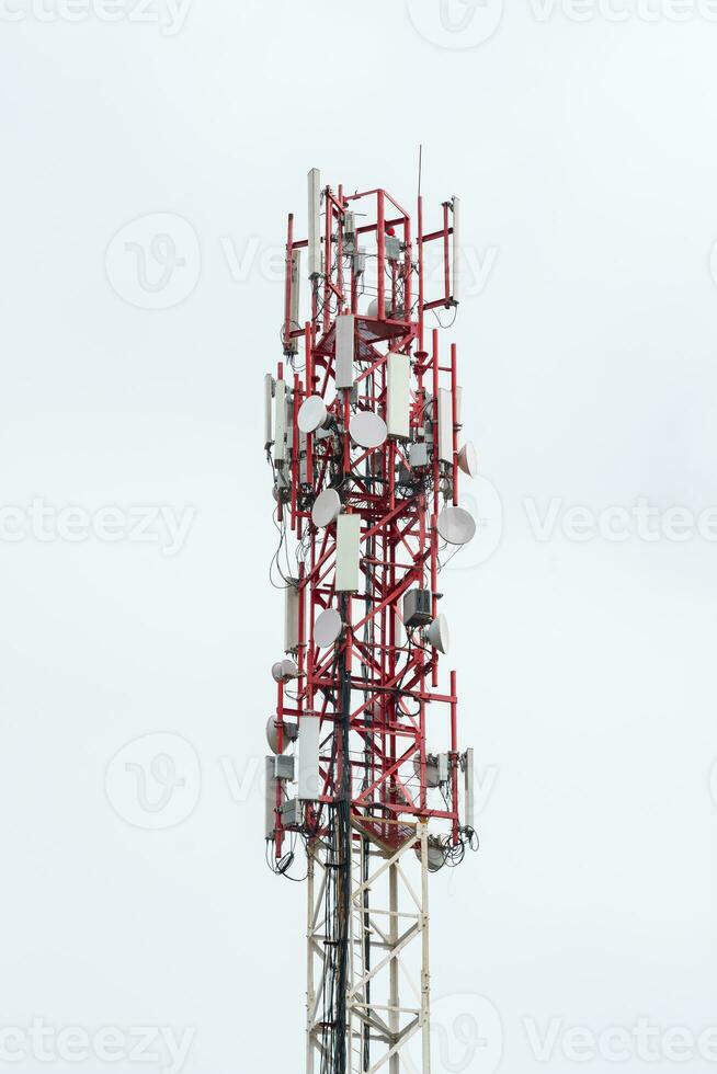 upper part of the radio tower with installed antennas and other equipment against a white cloudy sky photo