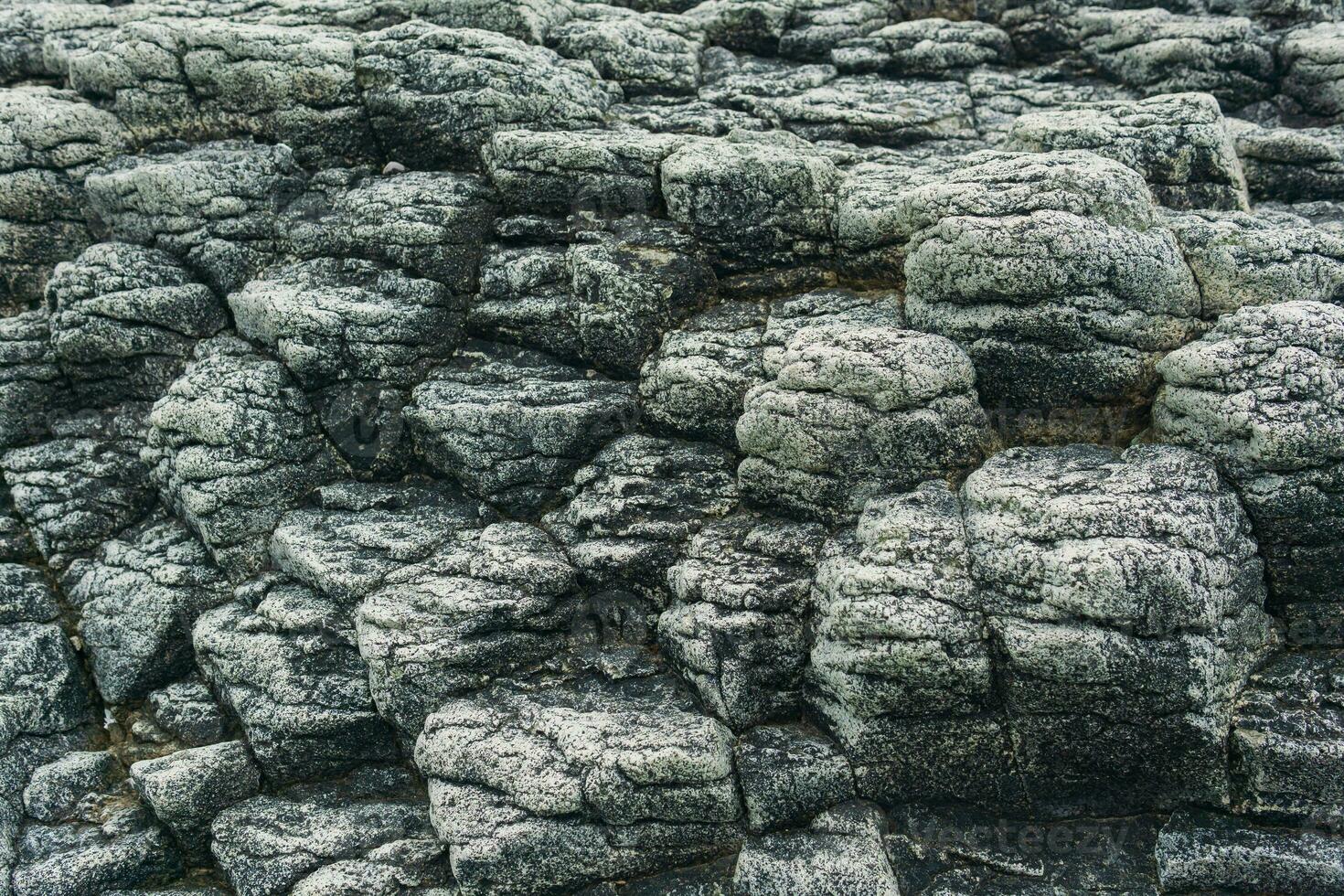 natural stone background, the remains of lava basalt columns form a relief surface photo