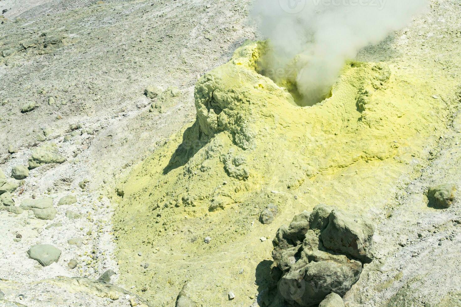 yellow cone of crystallized sulfur around a smoking solfatara on the slope of a volcano photo