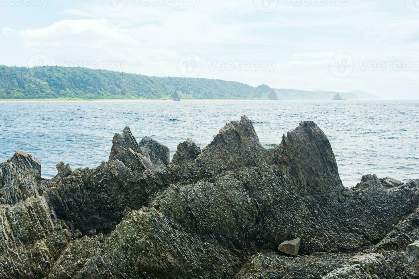 rocks formed by solidified lava against a blurred coastal seascape photo