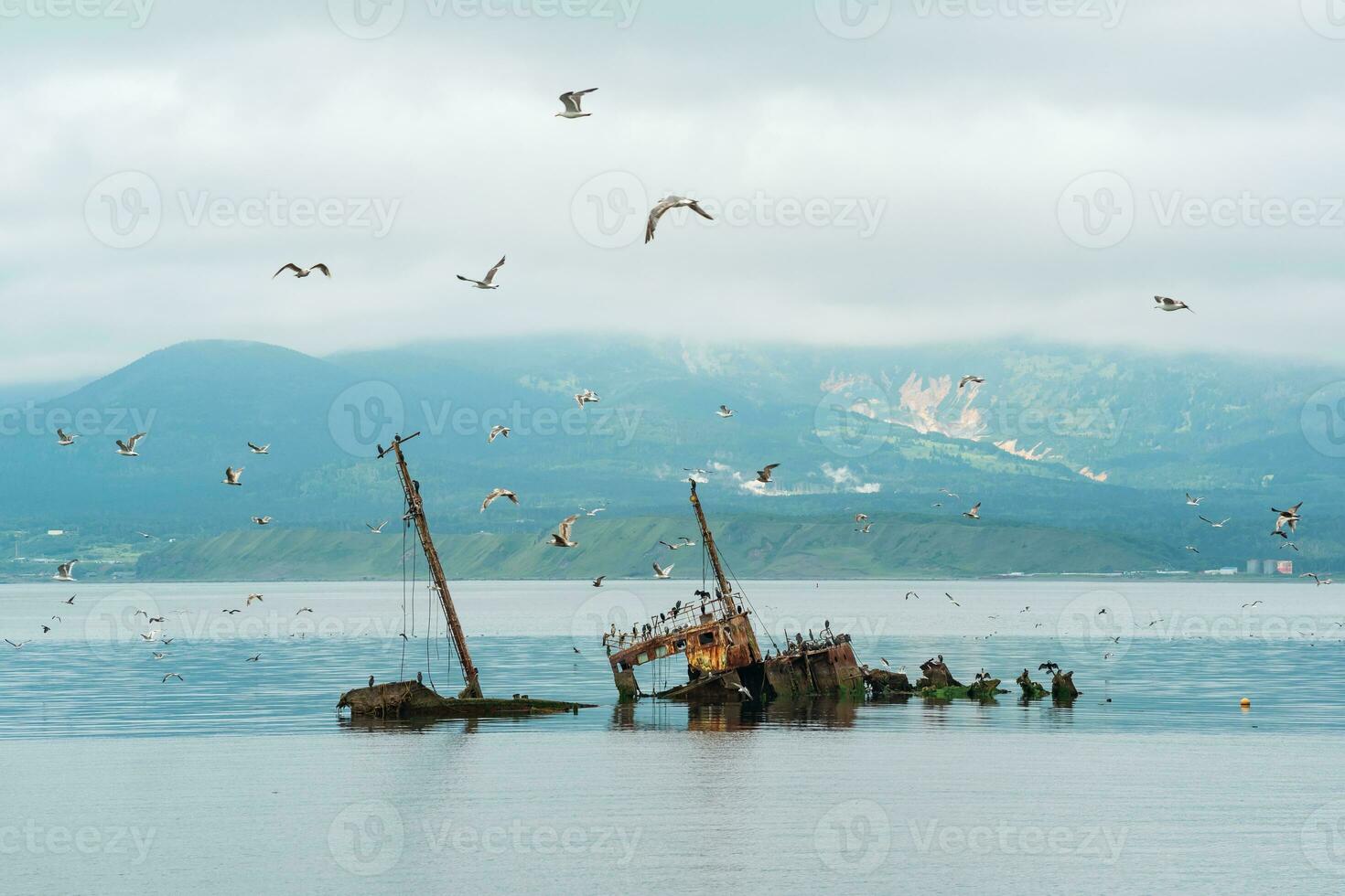 shipwreck against the backdrop of a sea bay with foggy mountains in the background photo