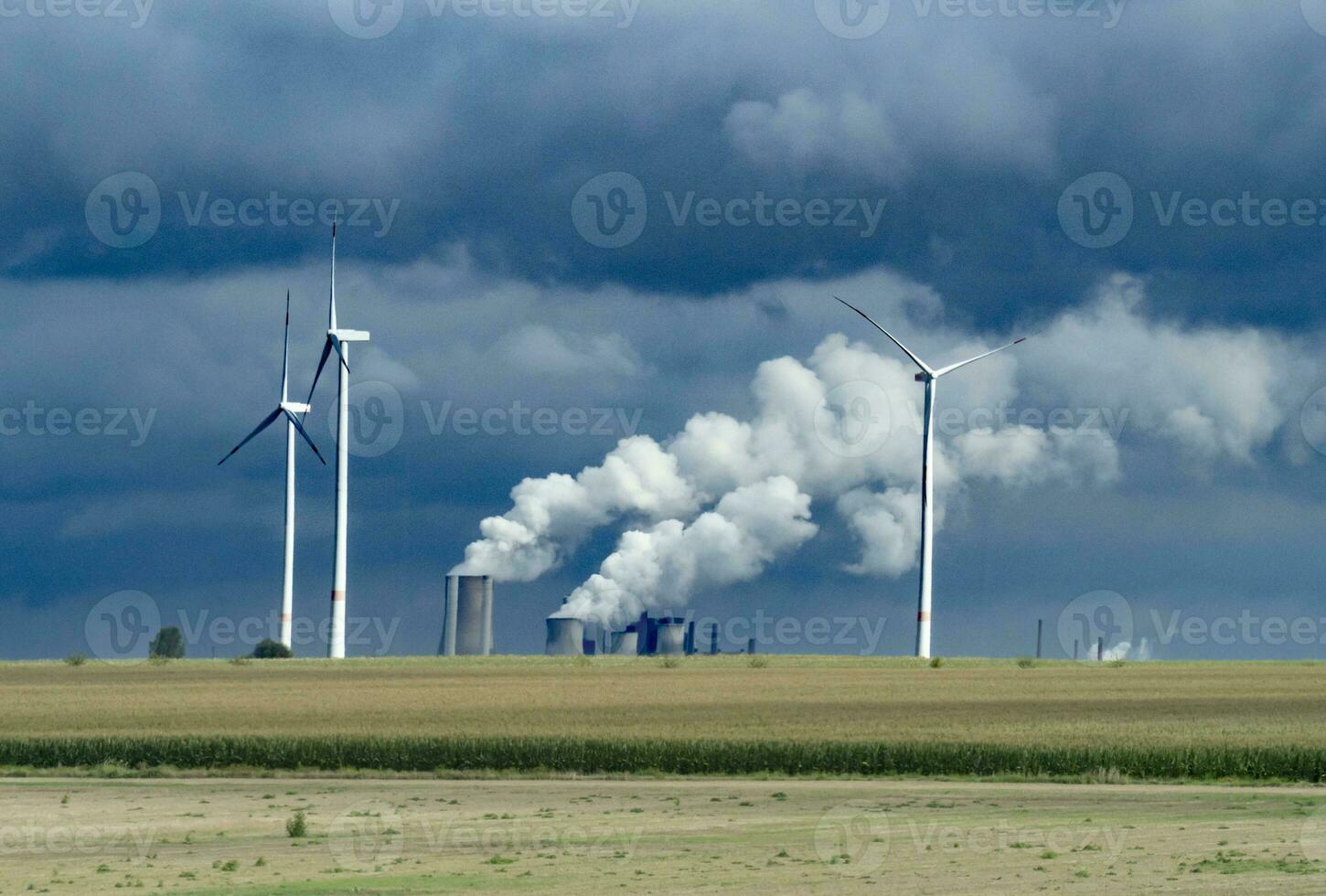 Wind turbines and industrial pipes with smoke on a cloudy day in Germany photo