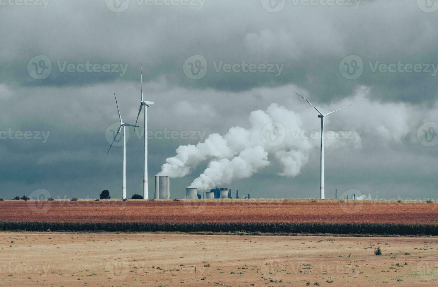 Wind turbines and industrial pipes with smoke on a cloudy day in Germany photo