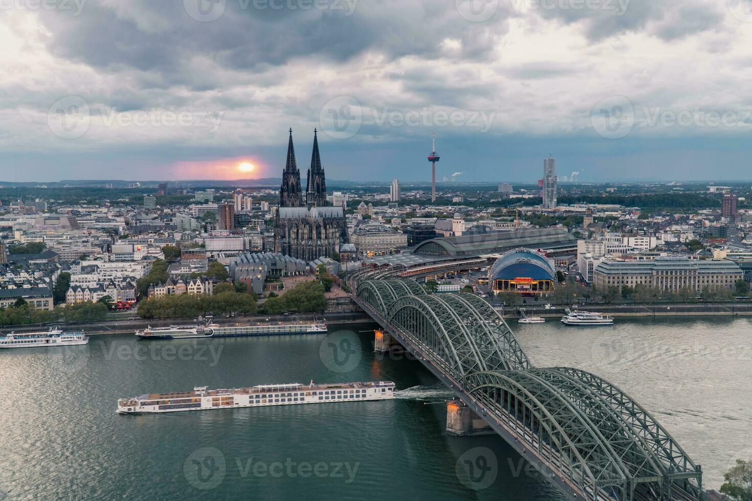 Dramatic storm clouds over Cologne Cathedral and Hohenzollern Bridge in the sunset photo