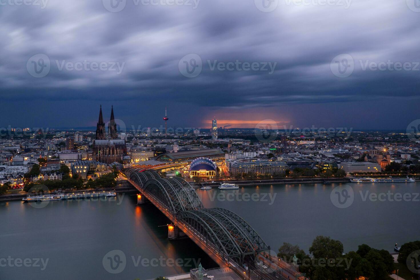 Dramatic storm clouds over Cologne Cathedral and Hohenzollern Bridge in the sunset photo