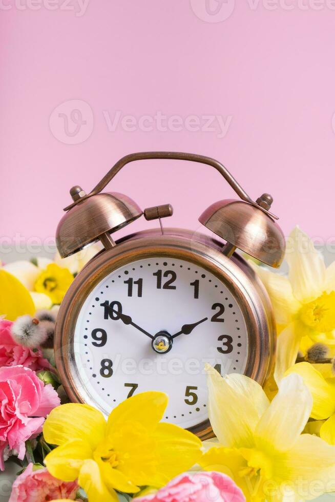 Alarm clock with spring flowers. Spring time, daylight savings concept, spring forward photo