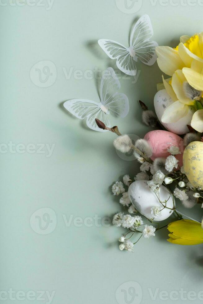 Daffodils, easter eggs and willow on green background with copy space. Easter greeting card template photo