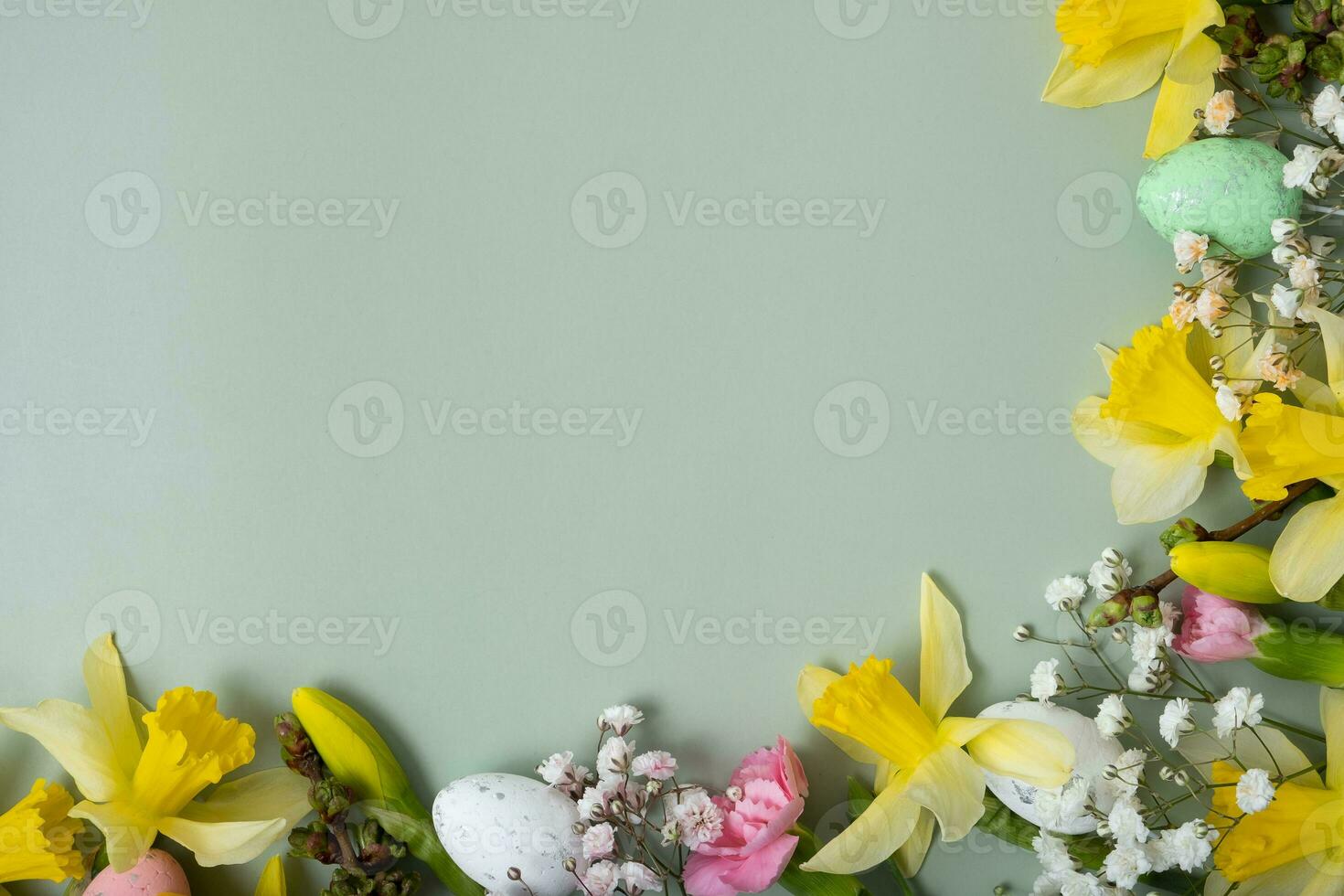 Spring flowers ans easter eggs border on green background with copy space. Easter greeting card template photo
