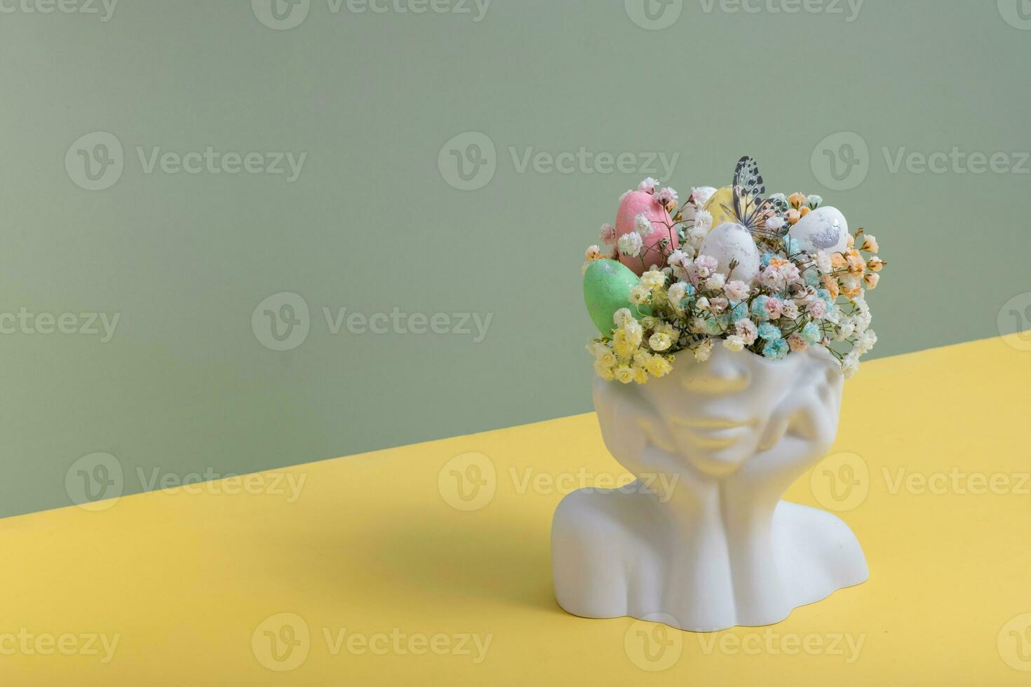 Plaster head statuette with Easter eggs and flowers. Easter creative concept photo
