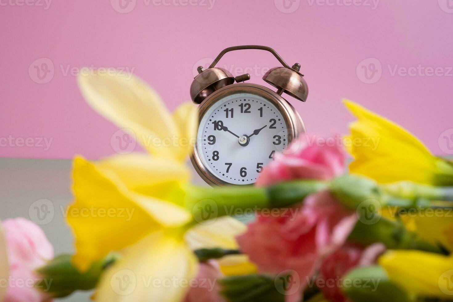 Alarm clock with spring flowers. Spring time, daylight savings concept, spring forward photo